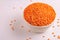 Raw red lentils in clay bowl on white marble background