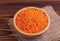Raw red lentils in wooden bowl with burlap napkin