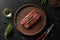 Raw ribeye steak on cutting board with rosemary on black background