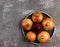 Raw ripe onions bulbs on a round plate on a dark background