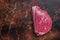 Raw rump beef cut or top sirloin meat steak on butcher table. Dark background. Top view. Copy space