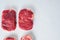 Raw rump steak. Organic beef. White textured background. Top view with space for text