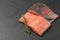 Raw salmon fillet on a dark slate background. Trout fillet with rosemary. Wild atlantic fish