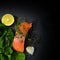 Raw salmon fillet with thyme, garlic, lemon and spinach on a dar