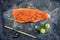 Raw salmon fish steak with ingredients like lemon, pepper, sea salt and dill on black board, sketched image with chalk of salmon f