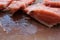 Raw salmon slices melting on a wooden cutting board. Top view of frozen pieces of red fish