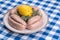 Raw sausages, 12 linked on a plate with lemon and sage garnish