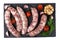 Raw sausages on black slate with grilled tomatoes and spices isolated on white background