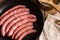 Raw sausages in iron cast pan, rice in copper pot, linen towel on wood kitchen table, top view