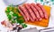 Raw sausages longaniza with greens, garlic and spices on wooden cutting board