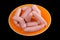 Raw sausages,orange plate,black background