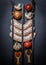 Raw sausages with skewers, different vegetables, spices and ingredients on a black background