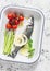 Raw sea bass, cherry tomatoes and asparagus in the baking tray. Ingredients for lunch. On a light background