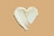 Raw shea butter moisturiser cream smear texture stroke heart shape on brown beige background