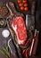 Raw sirloin beef steak on vintage chopping board with knife and fork on rusty background. Salt and pepper with fresh rosemary and