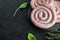 Raw snail sausage in traditional spiral  on black background   with space for text copyspace