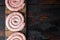 Raw snail sausage in traditional spiral  on old dark wooden table background  top view flat lay   with space for text copyspace