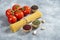 Raw spaghetti, spices and tomatoes on marble background