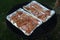 Raw spiced chicken breast slices prepared for barbecue on perforated thing aluminium grill plate.