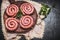 Raw spiral sausages on wooden cutting board, top view