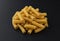 Raw spiral tortiglioni pasta isolated on black background