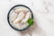 Raw squid fillet in a bowl over marble background. Small calamary tubes prepared for cooking. Fresh squid molluscs ingredient for