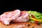 Raw steak, chop on a rustic cutting board with salt, pepper and grinder for spices . Black Background for copy space