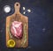 Raw steak on a cutting board with a fork, with rosemary , oil, garlic, salt and pepper rustic wooden background, top view