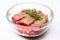 raw steak in a glass bowl, coated with herb rub