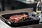 Raw steak lay at griddle pan. Closeup uncooked beef lay at pan.