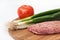 Raw stuffed hamburger on wooden board with tomatoes and onions