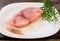 Raw Swordfish fillet covered with black pepper and with rosemary sprigs on white plate