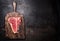 Raw T-bone steak on aged wooden cutting board on dark rust metal background, top view