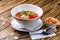 Raw tomato soup, typical food of Spain, served in white bowls with pieces of tomato, cucumber and paprika. Wooden
