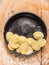 Raw Tortellini in black plate on wooden background with wheat flour