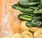 Raw Tortellini with fresh spinach leaves on wooden background with wheat flour, top view