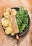 Raw Tortellini with Rolling pin and fresh spinach leaves in gray plate on wooden background with wheat flour