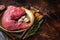 Raw tri-tip triangle roast or bottom sirloin steak on plate with herbs. Dark background. Top view. Copy space