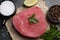 Raw tuna fillet, parsley and spices on black table, flat lay