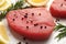 Raw tuna fillet with peppercorns, lemon and rosemary on white table, closeup