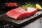 Raw tuna fish fillet with rosemary, pepper and lemon on black wooden background, closeup view of a fresh raw tuna steak on cutting