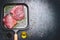 Raw Tuna Steak in grill frying pan with herbs and oil on dark aged vintage background, top view