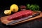Raw tuna steak with lemon and basil on cutting board