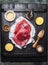 Raw tuna steak with lemon ,oil and ingredients for cooking on dark wooden background