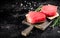Raw tuna steaks on a rosemary cutting board.