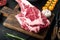 Raw uncooked black angus beef tomahawk steak on bone, with grill ingredients, on black wooden table background