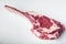 Raw uncooked black angus beef tomahawk steak on bone, on white stone  background, with copy space for text