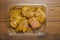 Raw uncooked lemon and coconut marinated chicken fillets in a plastic tray on a wooden table. Poultry product. Meat industry,