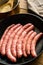 Raw uncooked pork and chicken sausages, Spanish longaniza, in iron cast pan