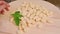 Raw uncooked potato gnocchi with flour and grated parmesan cheese over wooden board . Close up. Home cooking